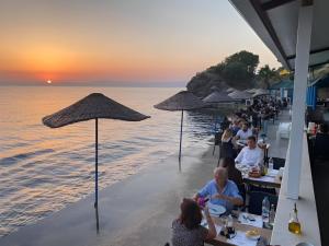 a group of people sitting at tables on the beach at Dubleks villa in Gomec