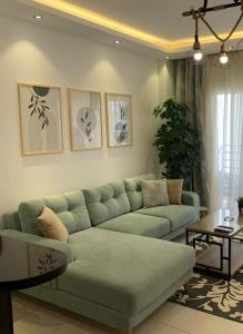 a living room with a green couch and a table at Lovely Cosy 1 Bedroom in Stella Sidi Abdelrahman families only in El Alamein