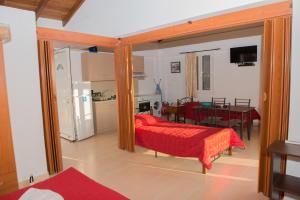 1 dormitorio con cama roja y comedor en Villa Oniro Kreta, en Kalamaki