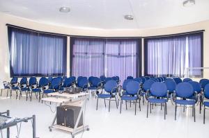 a room with blue chairs and a tv in it at Ferian Plaza Hotel in Itapira