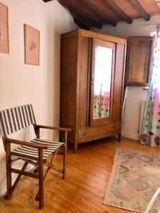 une chambre avec une chaise, une armoire et une fenêtre dans l'établissement Tenuta di Corsano, à Monteroni dʼArbia