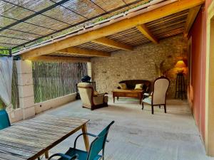 a patio with chairs and a table and a wooden ceiling at Domaine Plan des Devens in Roussillon
