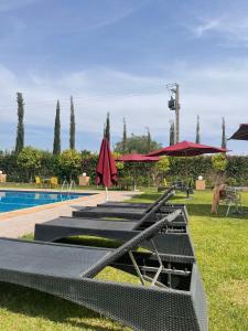 una piscina con mesas y sombrillas junto a en Palais Benfatah, en Marrakech 78 fotos más