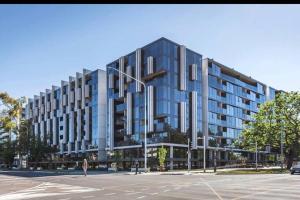 a large glass building on a street with a parking lot at 112 at Plush Midnight in Canberra