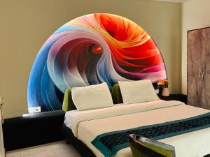 a bedroom with a bed with a colorful mural on the wall at THE ROYAL PRESIDENCY INN in Lucknow