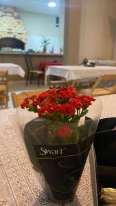 a vase filled with red flowers on a table at Pousada e Espaco AURORA Peruibe in Peruíbe