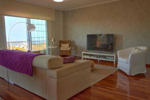 ein Wohnzimmer mit einem Sofa und einem TV in der Unterkunft Casa con piscina, vistas y cerca de las playas in Vigo