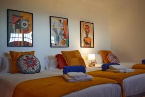 2 Betten in einem Zimmer mit Gemälden an der Wand in der Unterkunft Casa con piscina, vistas y cerca de las playas in Vigo