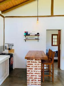 uma cozinha com um balcão de tijolos e uma mesa em Chale Vale das Cachoeiras em Capitólio