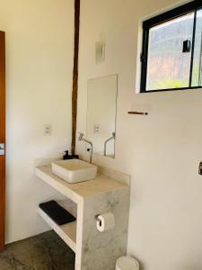 ein Badezimmer mit einem weißen Waschbecken und einem Spiegel in der Unterkunft Chale Vale das Cachoeiras in Capitólio
