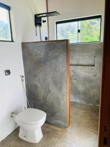 a bathroom with a toilet and a shower with a window at Chale Vale das Cachoeiras in Capitólio