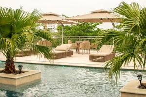 a pool with chairs and tables and palm trees at Hotel Unión Plaza in Montería