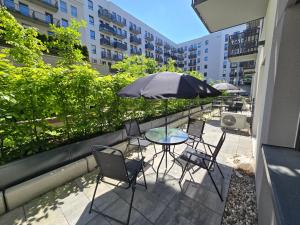 eine Terrasse mit einem Tisch, Stühlen und einem Sonnenschirm in der Unterkunft Szczecin Apartamenty Aparthotel D'orski in Stettin