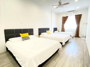een kamer met 3 bedden met witte lakens en gele kussens bij Grace Homestay Tawau in Tawau