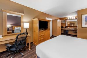 Habitación de hotel con cama, escritorio y TV. en Best Western Plus Stovall's Inn en Anaheim