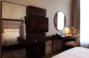 a bedroom with a bed and a television and a mirror at Glasgow Grosvenor Hotel in Glasgow