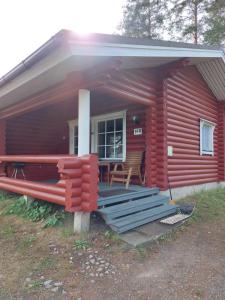 Cabaña de madera roja con porche y banco en Pankkotupa 16-B en Punkaharju