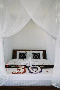 a bed with a white canopy with flowers on it at Papahan Bali in Sidemen