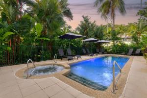 einen Pool mit Stühlen und Sonnenschirmen in einem Resort in der Unterkunft Port Douglas Apartments - Adults Only Oasis in Port Douglas