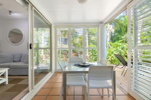 a dining room with a glass table and chairs at Port Douglas Apartments in Port Douglas