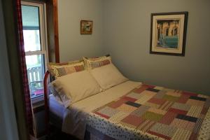 a bedroom with a bed with a quilt and a window at Spry Church Cozy Cottage in Lion's Head