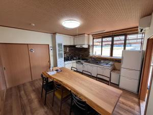 una cocina con una larga mesa de madera en una habitación en Villa KUMANO, en Hongū