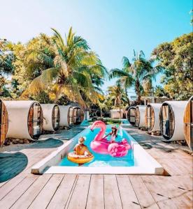 a pool at a resort with two people on a pink flamingo at Kulu Tubohostel Bacalar in Bacalar