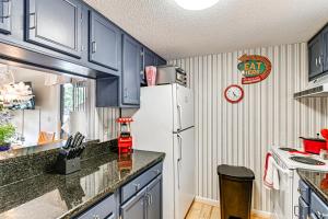 a kitchen with blue cabinets and a white refrigerator at Lakeview Condo with Resort Pool 2 Miles to Golf! in Pinehurst