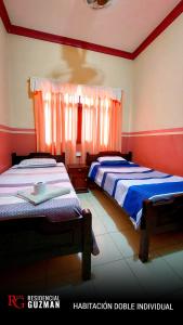 Duas camas num quarto com paredes vermelhas e brancas em Residencial Guzmán 1 em Yacuiba