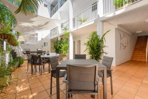 un restaurante con mesas, sillas y plantas en Port Douglas Apartments, en Port Douglas