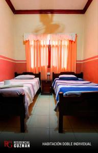 2 camas en una habitación con paredes de color naranja en Residencial Guzmán 1 en Yacuíba