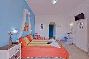 a bedroom with a bed with an orange bedspread at Aelia Studios in Koukounaries