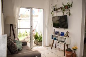 ein Wohnzimmer mit einem Sofa und einem TV in der Unterkunft Apartamento Cactus no Dallas Park in Campina Grande