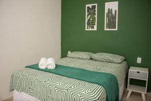 ein Schlafzimmer mit einem Bett mit einer grünen Wand in der Unterkunft Apartamento Cactus no Dallas Park in Campina Grande