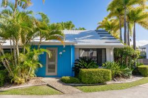 a blue house with palm trees in front of it at 1 Bedroom Ground Level Unit in Noosaville Resort in Noosaville