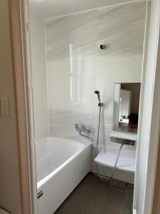 a white bathroom with a tub and a sink at リベルテ Work & Vacation Villa Nosoko in Ibaruma +9 photos