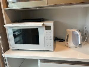 a white microwave oven sitting on top of a counter at リベルテ Work & Vacation Villa Nosoko in Ibaruma