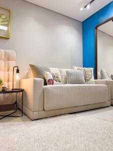 sala de estar con sofá blanco y espejo en Loft luxuoso na Serra - Granja Brasil Resort itaipava - Petrópolis en Petrópolis