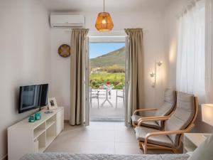 a living room with a bed and chairs and a television at Amouage Studios in Kampos Paros