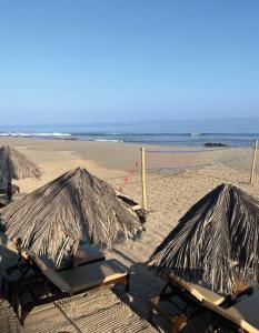 dwa leżaki i parasole na plaży z oceanem w obiekcie Los Corales w mieście Máncora