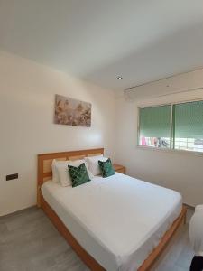 1 dormitorio con 1 cama blanca grande y 2 almohadas verdes en Appart happiness family only en Tánger