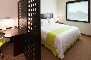 um quarto de hotel com uma cama grande e uma secretária. em Holiday Inn Express Guadalajara Iteso, an IHG Hotel em Guadalajara