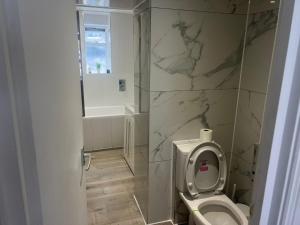 a bathroom with a toilet and a marble wall at Harrington Apartments in Central London in London