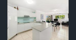 a kitchen with white cabinets and a living room at Blue Waters Apartments in Gold Coast