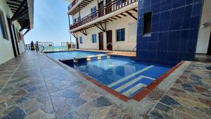 a swimming pool next to a building with the ocean at Hotel Juanmar in Juan de Acosta
