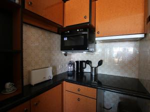a kitchen with a black counter top and a microwave at Studio cosy avec balcon à Saint-Brevin, 3 pers. - FR-1-364-137 in Saint-Brevin-les-Pins