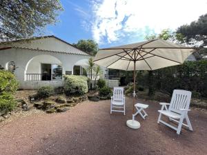 zwei Stühle und ein Sonnenschirm vor einem Haus in der Unterkunft Maison lumineuse avec jardin près de la plage - 4 couchages, quartier calme, St Brévin L'Océan - FR-1-364-136 in Saint-Brevin-les-Pins
