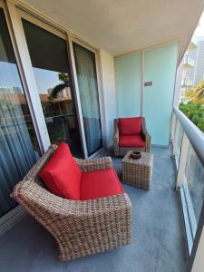 balcón con sillas de mimbre y almohadas rojas en Beachwalk Resort & Condos, en Hallandale Beach