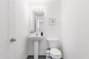 La salle de bains blanche est pourvue de toilettes et d'un lavabo. dans l'établissement New Luxury Suite 6Mins To Falls, Free Parking, à Niagara Falls