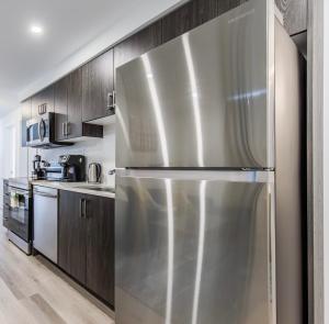 een roestvrijstalen koelkast in een keuken met houten kasten bij New Luxury Suite 6Mins To Falls, Free Parking in Niagara Falls